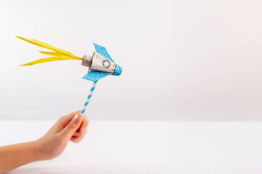 a close up of a person holding a paper rocket, with a white background, recycled, egg carton craft, fun toy making, project for kids,  clipart