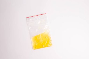 Beyaz bir yüzeyde plastik bir torbaya yakın çekim, minimalizm, içinde sarı sıvı, üst görünüm