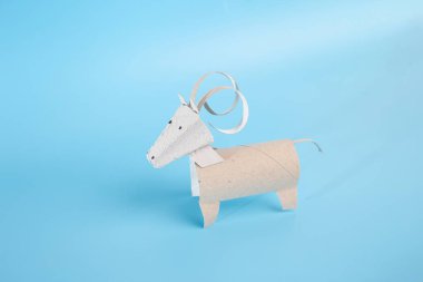 Çocuklar ve anaokulları için ev yapımı bir kağıt işçiliği dersi içeren tuvalet kağıdı rulosu konsepti. Kendi koçunu, dağ keçini ya da keçi oyuncağını yap. Mavi boynuzlu yaratık. 