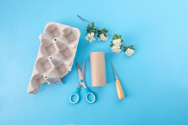 Natural materials for childrens creativity. empty toilet paper roll, egg carton box, white flowers, scissors and awl clipart