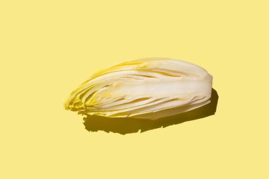 Hindiba salatası hindiba, yarım parça, üst görünüm, soluk sarı arkaplan, doğrudan güneş ışığı sert gölgeleri, kopyalama alanı