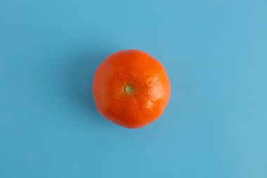 Mavi yüzey üzerinde bir mandalina, üst görünüm