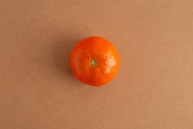 Bir mandalina masanın üstünde oturuyor, en üstte.