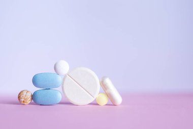 Masadaki hapları kapat, figür libre tarzı, mavi ve pembe renk şeması. Sanatsal ve modern yaklaşımlı sağlık, ilaç ve ilaç tartışmaları için mükemmel..