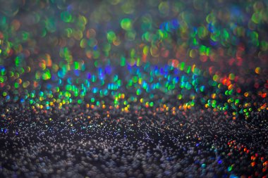 Resim, dokulu yüzeyde bokeh etkisi yaratan dairesel ışık yansımalarının çokluğunu gösterir. mavi, yeşil, kırmızı, sarı, sığ alan derinliği, yumuşak odak, ışıl ışıl etkisi.