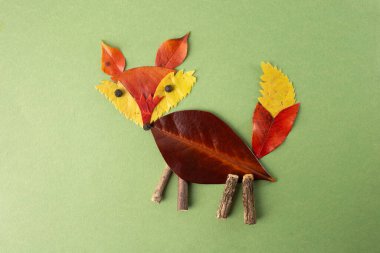 Fox creatively represented with autumn leaves on green background, funny character made by child, autumn craft for kids, ideas for preschooler activities  clipart