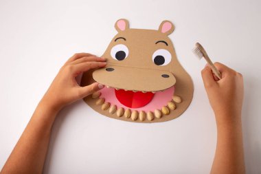 Diş sağlığı için DIY zanaatı ve ilköğretim için diş sağlığı: geniş ağızlı kağıt yapımı hipopotam kafası, şam fıstığı mukavvası, diş fırçası, çocuklara diş hijyeni, eğlence ve eğitim hakkında öğretim.
