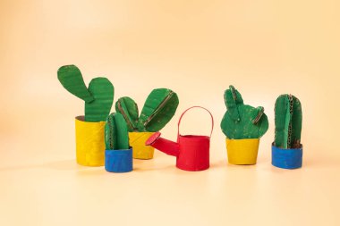 Bir grup kaktüs yan yana oturuyor, kavramsal sanat, oyuncak tasarımı, sarı bir kanvanın üzerinde, ürün fotoğrafı, kartondan kesilmiş, sulama kutusu, çocuk, 