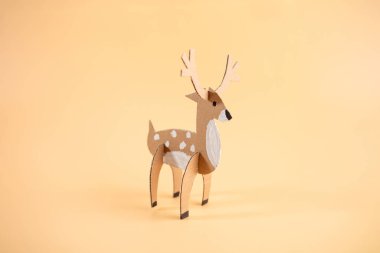 paper craft model of a deer on a plain orange background, recycling concept, fun project for anyone interested in crafts or animal models, clipart