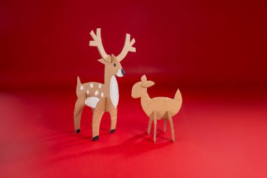 Yaratıcı el işi projesi, üç boyutlu geyik kâğıdı modeli, çentik, kesik ve katlanmış karton, beyaz lekeli açık kahverengi, koyu kırmızı arka plan, güzel geyik ya da geyik, çocuklar için Noel aktivitesi