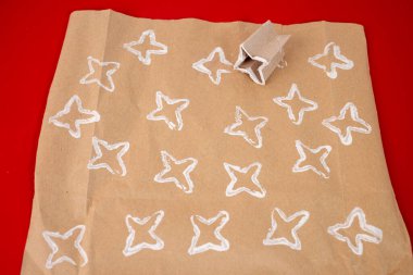 Kağıt rulolarını şekillere katlayarak yıldızları şekillendirmek, çocuklar için DIY projesi, orijinal ambalaj kağıdı yapmayı öğretmek. Geri dönüştürülmüş materyaller, eğlence ve yaratıcı tasarımlar için basit etkinlikler.
