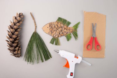 Balık şeklinde kesilmiş bir karton parçası, kartondan şekiller kesmeyi içeren basit bir zanaat aktivitesini gösteriyor, gri arka plan, yukarıdan aşağıya görünüm