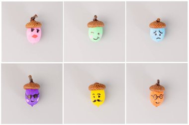 Açık gri arkaplanda bir ızgara düzeninde çeşitli yüz ifadeleriyle farklı renkte meşe palamutları boyadım. DIY ve el işi projeleri için. Sonbahar ve mevsimlik dekorasyon konsepti. Ders görüntüsü