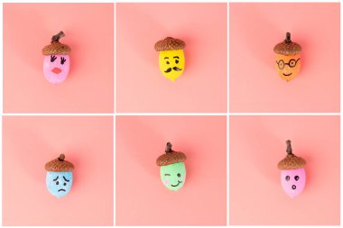 Elle boyanmış meşe palamutları ve pembe arka planda düzenlenmiş çeşitli yüz ifadeleri. DIY ve el işi projeleri için. Sonbahar ve mevsimlik dekorasyon konsepti. Düz konum