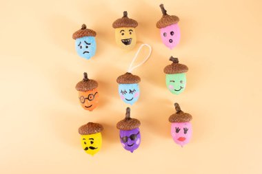 Şeftali arka planında yüz ifadeleri olan renkli meşe palamutları. Autumn DiY zanaat fikri, düz yatış. Çocuk aktivitesi için mükemmel, DIY, el işi, üst görünüm