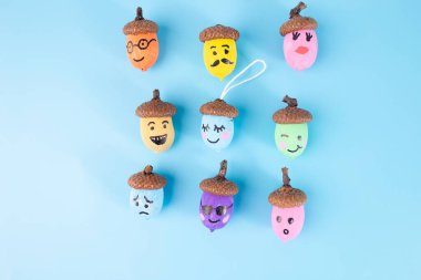 Yüzlü palamutlar, çeşitli renkler, 3x3 ızgara, açık mavi arkaplan, kahverengi şapkalar, mutlu, üzgün, şaşırmış ifadeler, yaratıcı sonbahar zanaatı, kaprisli doğa sanatı, dekorasyon