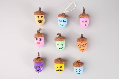 Renkli meşe palamutları ve gri arka planda emoji yüzleri. Autumn DiY zanaat fikri, düz yatış. Çocuk aktivitesi için mükemmel, DIY, el işi, üst görünüm