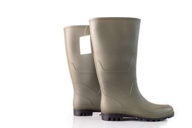 Bir çift zeytin yeşili lastik bot ve beyaz arka planda izole edilmiş boş bir etiket. Tasarım ve baskı için stüdyo ürünü fotoğrafçılığı, yan görünüm, düşük açı, kapat