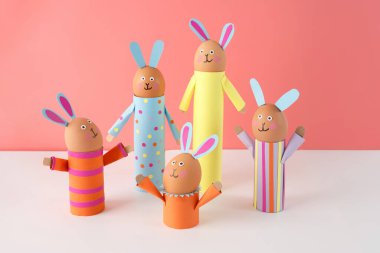 El yapımı Paskalya tavşanları ailesi geri dönüştürülmüş karton tüplerden yapılmış, pembe arka plan, Paskalya kutlaması ve DIY el işi konsepti. Çocuklar için bahar etkinliği