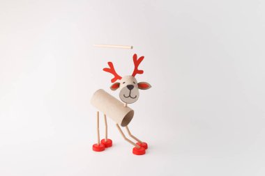 Karton tüplerden, kırmızı plastik şapkalardan ve kağıt detaylarından yapılmış DIY ren geyiği kuklası. Beyaz bir arka planda stüdyo çekimi. Noel zanaatı ve tatil dekorasyonu konsepti