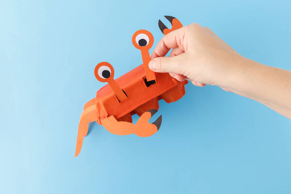 step in creative process, hand attach paper details for legs, claws, and eyes for Recycled crab craft using egg carton, Fun eco-friendly DIY idea