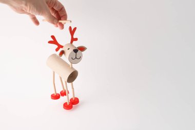 Karton tüplerden, plastik şapkalardan ve kağıttan yapılmış ren geyiği kuklası. Beyaz arka planda stüdyo çekimi. Noel zanaatı ve tatil dekorasyonu. Çocuklar ve aileler için eğlenceli geri dönüşümlü proje.