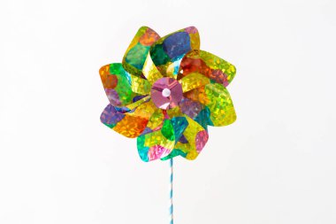 Close-up of holographic pinwheel set against white backdrop with space for text. Bright summer, childhood, and playful design concept suited for print, digital design, and marketing visuals clipart