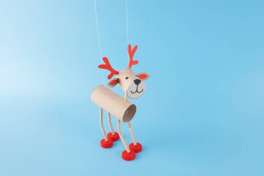 Yapması kolay bir aktivite, çocuk ve anaokulu için Noel geyiği tuvalet kağıdı rulosu, DIY, geri dönüşümlü malzemelerden kukla, karton tüplerden yapılmış kukla, plastik kapaklar, mavi arka plan. 