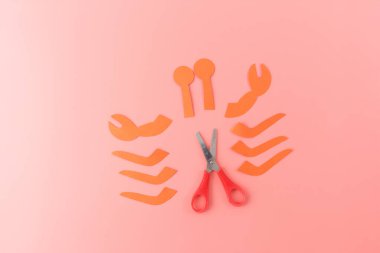 an arrangement of orange paper cutouts on a pink background, six curved shapes, representing the crabs legs. simplicity and creativity, context of art or design. step in creative process in progress clipart