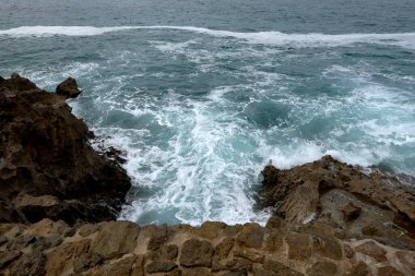 Çakıl taşlı bir yolda dalgalar kıyıya vuruyor. Su köpüğü, vahşi sular, doku, okyanus, deniz, kayalar, tehlike