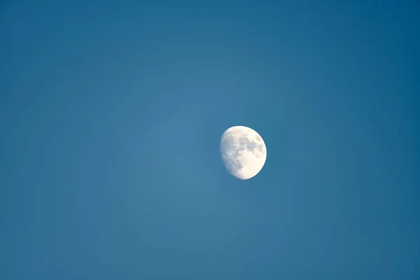 An almost full moon on a blue background. Background, contrasts, nobody, empty space, clear,
