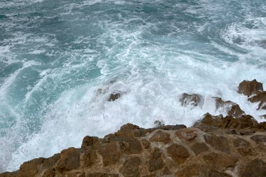 Çakıl taşlı bir yolda dalgalar kıyıya vuruyor. Su köpüğü, vahşi sular, doku, okyanus, deniz, kayalar, tehlike