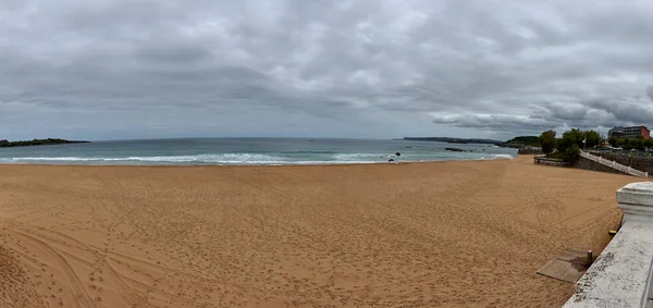 Camel beach, Santander, Spain, on cloudy day. Calm waters, no people, sand rocks and small waves