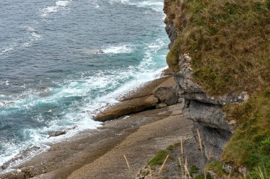 Cantabrian Denizi kıyısında bir deniz feneri, ve kıyı şeridi, sakin sular, kıyıda dalgalar, bitki örtüsü, uçurumlar