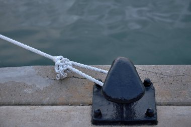 Limandan beyaz bir iple bağlanmış bir kazık. Detaylar, çizgiler, münzevi, cuerda blanca, renkli metalik, mar şeffaf