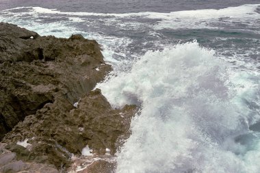 Çakıl taşlı bir yolda dalgalar kıyıya vuruyor. Su köpüğü, vahşi sular, doku, okyanus, deniz, kayalar, tehlike