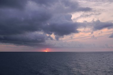 Bulutlu bir günde Akdeniz 'de gün batımı. Okyanus, yağmur bulutları, ufuk çizgisi, boş uzay, soğuk tonlar, mavi, turuncu güneş ışığı.