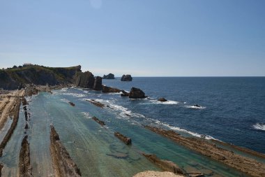 Beach of Liencres, Costa Quebrada, on a sunny day. geological formations, cliffs, no people, lines, cloudless sky
