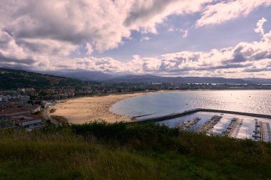 Bir yaz gününde Laredo köyü. Güneşli, mimari, alçak gelgit, bulutlu ve güneşli gökyüzü, yeşillik.