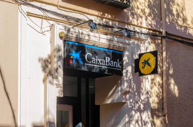 SAN LORENZO DE EL ESCORIAL, İspanya - 24 Ekim 2021: Caixabank logosu San Lorenzo de El Escorial, İspanya 'da bir banka şubesinde. CaixaBank, İspanyol çok uluslu finans hizmetleri şirketidir.