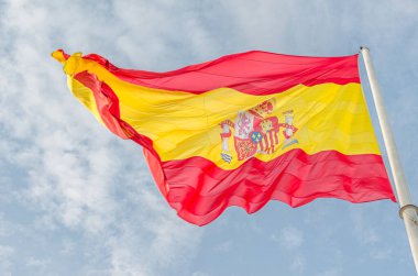Bulutlu mavi arka planda rüzgarda dalgalanan İspanyol bayrağı