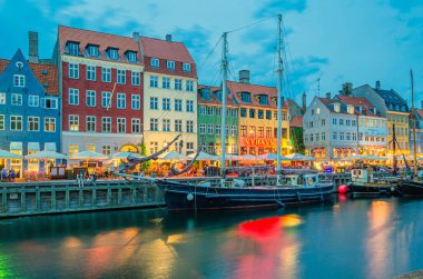 COPENHAGEN, DENMARK - 8 Temmuz 2014: Danimarka 'nın Kopenhag kentindeki 17. yüzyıl rıhtım, kanal ve eğlence bölgesi Nyhavn' daki renkli evler, barlar ve restoranların alacakaranlıkta görülmesi