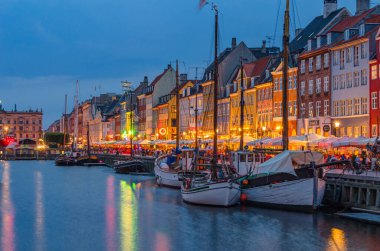 COPENHAGEN, DENMARK - 8 Temmuz 2014: Danimarka 'nın Kopenhag kentindeki 17. yüzyıl rıhtım, kanal ve eğlence bölgesi Nyhavn' daki renkli evler, barlar ve restoranların alacakaranlıkta görülmesi