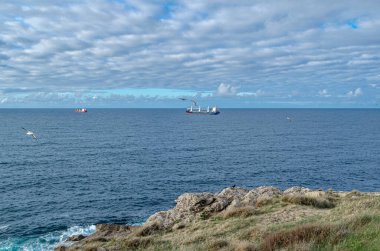 Santander 'in yeşil, kayalık kıyıları, Cantabria, Kuzey İspanya, arka planda tekneler
