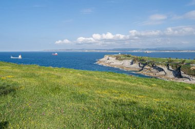 Santander 'in yeşil, kayalık kıyıları, Cantabria, Kuzey İspanya, arka planda tekneler