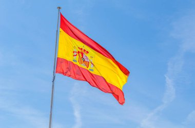 Mavi arka planda rüzgarda dalgalanan İspanyol bayrağı