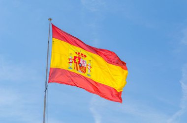 Mavi arka planda rüzgarda dalgalanan İspanyol bayrağı