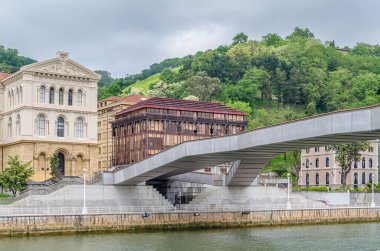 BILBAO, İspanya - 10 Mayıs 2014: Bilbao, İspanya 'daki Nervion Nehri üzerinden Pedro Arrupe yaya geçidi, Deusto Üniversitesi arka planda