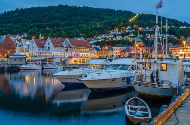 BERGEN, NORway - 16 Temmuz 2014: Vagen limanının arka planda Bryggen 'in renkli binaları ve Bergen, Norveç' te alacakaranlıkta görüntüsü. Bryggen, 1979 yılından beri UNESCO Dünya Kültür Mirası 'nda yer alıyor.
