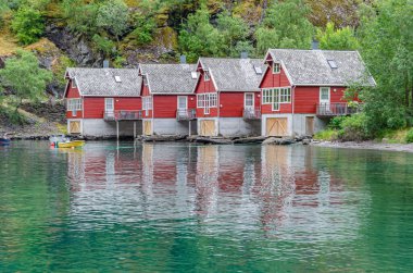 FLAM, NORway - 16 Temmuz 2014: Norveç 'in Vestland eyaleti Flam kasabasındaki Aurlandsfjord kıyısında kırsal kırmızı boyalı ahşap evler manzarası